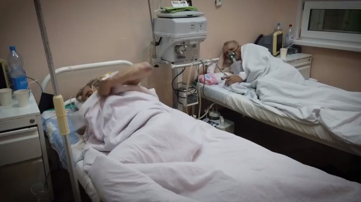 в палате на больничных кроватях лежат под белыми одеялами два пациента