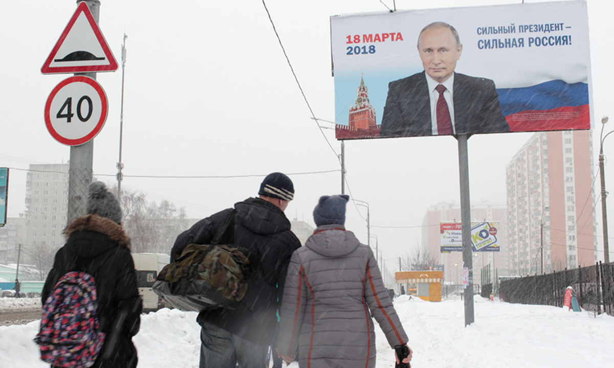 билборд с портретом Путина, под рекламой конструкцией стоят школьники спиной к камере