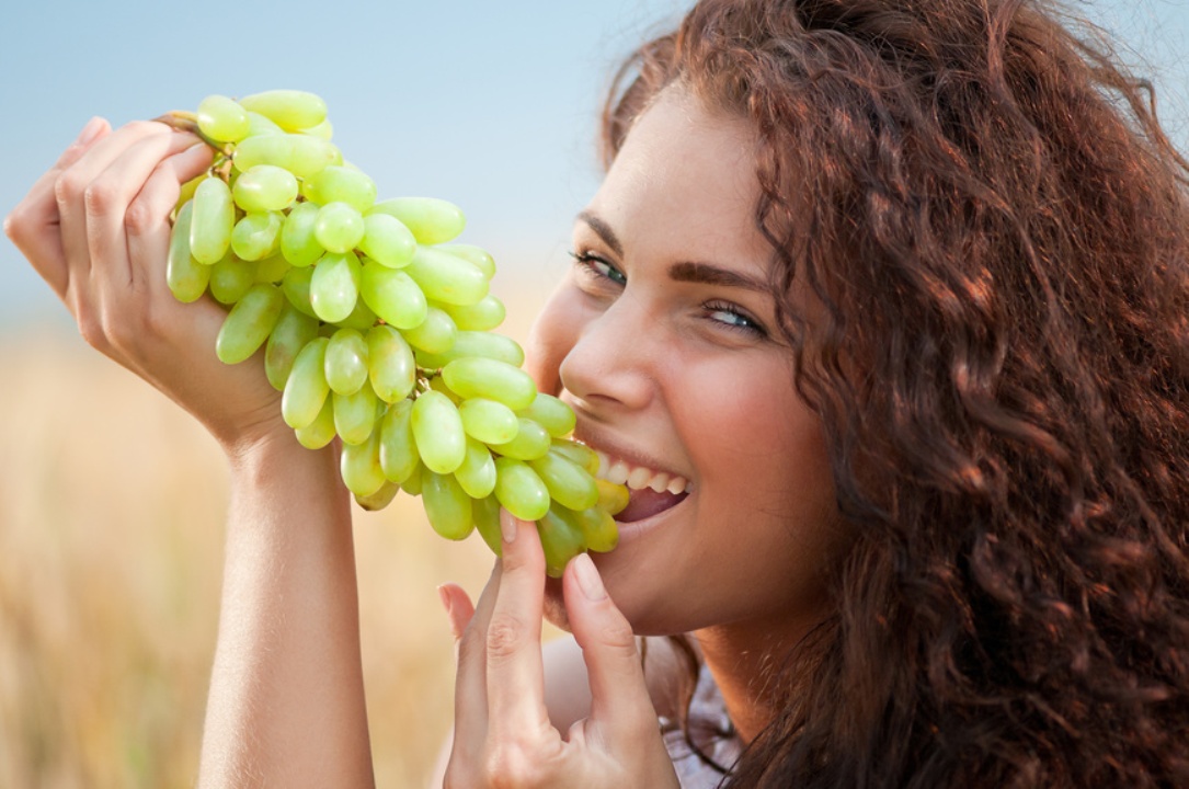 Девушка ест зеленый виноград