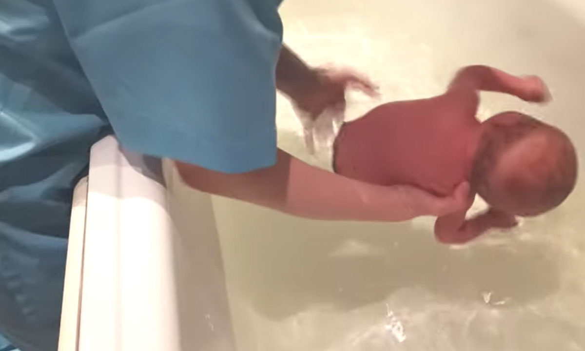 Ребенок захлебнулся водами. Ребенок захлебнулся в ванной. Купания младенца афроамериканца. Новорожденный подавился водой.